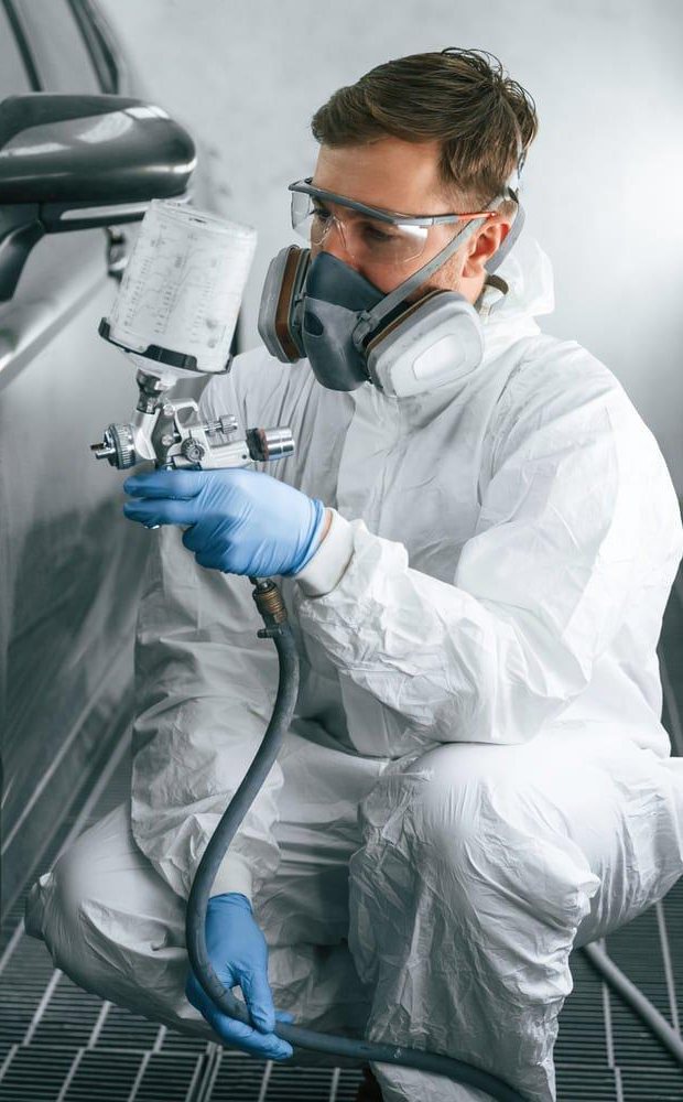 Painter spraying a car in the paint booth